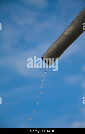 Tropfen Wasser aus Rohr - Nahaufnahme mit blauem Himmel. Konzept für die Wassermangel- und Umweltfragen. Kopieren Sie Platz zum Schreiben. Stockfoto