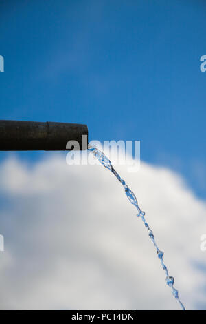 Tropfen Wasser aus Rohr - Nahaufnahme mit blauem Himmel. Konzept für die Wassermangel- und Umweltfragen. Kopieren Sie Platz zum Schreiben. Stockfoto