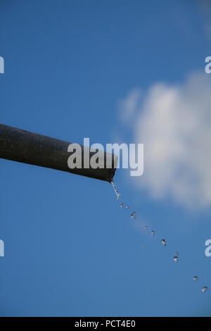 Tropfen Wasser aus Rohr - Nahaufnahme mit blauem Himmel. Konzept für die Wassermangel- und Umweltfragen. Kopieren Sie Platz zum Schreiben. Stockfoto