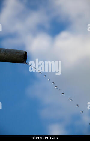 Tropfen Wasser aus Rohr - Nahaufnahme mit blauem Himmel. Konzept für die Wassermangel- und Umweltfragen. Kopieren Sie Platz zum Schreiben. Stockfoto