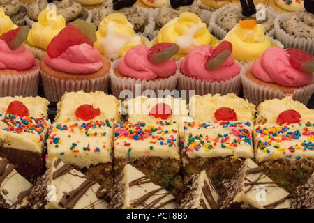 Eine attraktive lecker Anzeige der cup cakes in einer Vielzahl verschiedener Farben. Süßigkeiten, Kuchen und Süßwaren auf Anzeige am Marktstand. Stockfoto