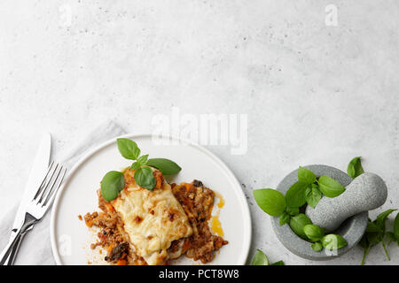 Traditionelle Fleisch Lasagne mit Hackfleisch, Sauce Bolognese und Bechamelsauce in Weiße, runde Platte am grauen Stein Hintergrund Stockfoto