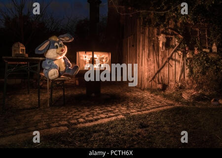 Große gefüllte Bunny auf Bier Sitzbank neben einer Feuerstelle im Garten von einem Bauernhof, Deutschland, Bayern Stockfoto