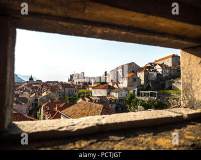 Schöne Aussicht auf die Altstadt von Dubrovnik Kroatien einschließlich Kirchen und Ton-ziegel roofed Häuser durch eine rechteckige Portal in die berühmte Mauer. Stockfoto