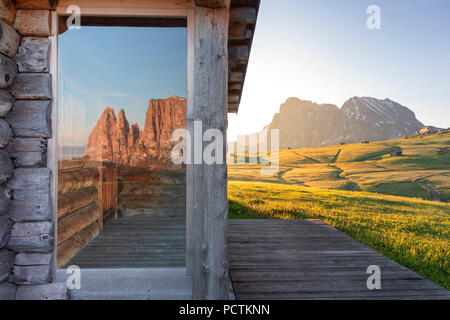 Europa, Italien, Bozen, Südtirol, Seiser Alm - Seiser Alm. Seiser Alm, den Schlern im Morgengrauen im Glas von einem Chalet aus Holz wider, im Hintergrund der Langkofel und Plattkofel/Plattkofel, Dolomiten Stockfoto