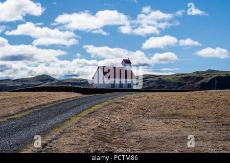 Kirche im alten Stil auf Island Landschaft Hintergrund. Weißes Gebäude mit rotem Dach auf wolkenbedecktem Himmel Stockfoto