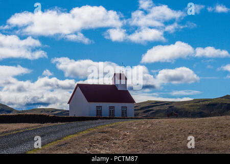 Kirche im alten Stil auf Island Landschaft Hintergrund. Weißes Gebäude mit rotem Dach auf wolkenbedecktem Himmel Stockfoto