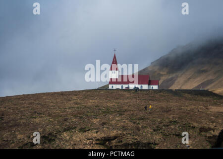 Kirche im alten Stil auf Island Landschaft Hintergrund. Weißes Gebäude mit rotem Dach auf wolkenbedecktem Himmel Stockfoto