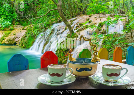 AKSU, Türkei - 9. Mai 2017: Die Bank von Kursunlu Wasserfall ist ideal, um die warme türkischen Kaffee in Osmanli Cafe mit seinen lustigen Schnurrbart ta zu genießen Stockfoto