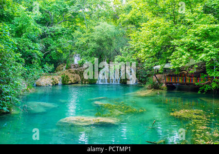 Die Bank der kleinen Wald See in Kursunlu Natur Park ist der beste Platz für das Picknick mit Blick auf den Wasserfall und üppiger Vegetation, Aksu, Türkei. Stockfoto