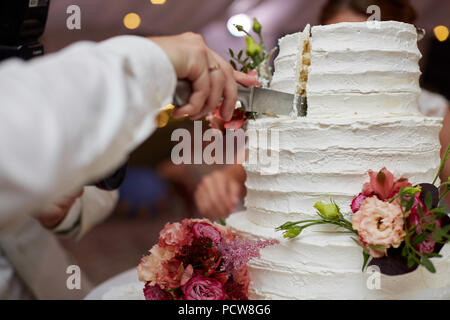 Braut und Bräutigam elegante Kuchen mit Rosen schneiden Stockfoto