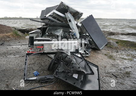 Begriff der Freiheit von der Computersucht - Mann bricht das Gerät von einem Computer mit einem Hummer außerhalb, See mit Wald Hintergrund. Zornigen Mann zerstören ein Laptop oder Computer mit einem Hammer. Stockfoto