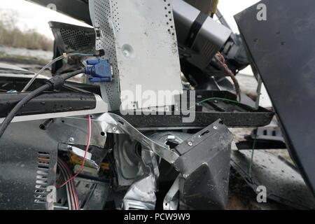 Defekten Computer, Monitore und Drucker vor der Natur Landschaft mit Fluss Hintergrund. Elektronische Geräte frei stehend in der Natur entsorgt. Computer Teile. Defekter Computer auf dem Boden im Freien Stockfoto