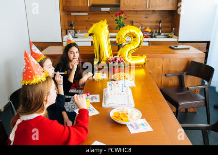 Gruppe Kinder feiern Geburtstag zusammen und bläst in die Pfeifen Stockfoto