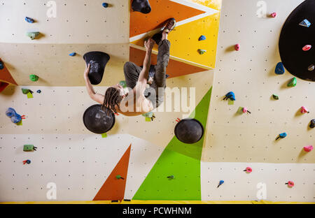 Junger Mann klettern Bouldern anspruchsvolle Route. In der Kletterhalle. Stockfoto