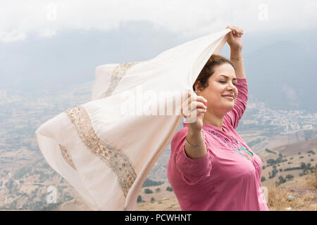 Frau mit geschlossenen Augen mit einem Schal in den Händen in der Natur und genießen von Wind Stockfoto