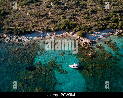 Blick von oben Luftbilder von einem Boot mit einigen entspannte Touristen an Bord schwimmend auf einer transparenten und türkisblaue Mittelmeer. Emerald Coast Stockfoto