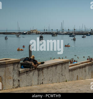 Obdachlosen Schlafen mit Blick auf die schöne Bucht und Luxus Yachten in Cascais Stockfoto