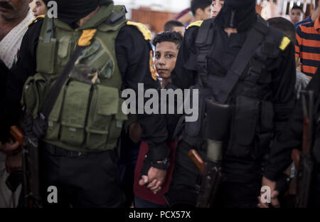 Gaza, Gaza, Palästina. 4 Aug, 2018. Kinder sitzen in der Nähe von Kämpfer von Al-Aqsa-Märtyrer-Brigaden, den bewaffneten Flügel der palästinensischen Fatah Bewegung während der Beerdigung von Ahmad Yaghi, der angeblich in Auseinandersetzungen mit israelischen Truppen war einen Tag zuvor getötet, in Gaza, den 04. August 2018. Berichten zufolge wurden zwei Palästinenser erschossen und mehr als 200 andere am 03. August bei Auseinandersetzungen verletzt nach Freitag zwischen israelischen Soldaten und Palästinensern Demonstranten in der Nähe der Grenze im Osten Gazastreifen Proteste. Credit: Mahmoud Issa/Quds Net News/ZUMA Draht/Alamy leben Nachrichten Stockfoto