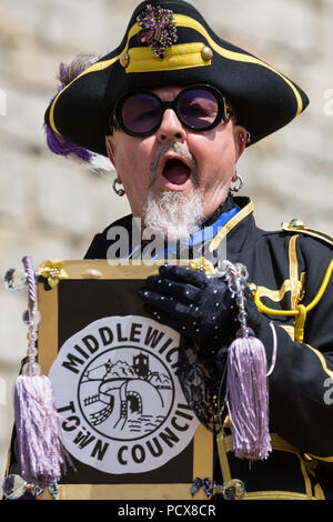 Windsor, Großbritannien. 4. August 2018. Devlin Hobson, Stadtausrufer von Northwich, beteiligt sich an der Antike und ehrenvolle Gilde Town Criers (AHGTC) nationalen Meisterschaft unter den Mauern von Schloss Windsor. 40 Town criers aus ganz Großbritannien und zwei aus Australien konkurrieren in zwei Runden von Weinen, die ersten, die ein Home Schrei auf Diktion, den Tonfall, die Klarheit und die Lautstärke und die zweite ein Schrei auf das Thema 'Feier' gezählt. Credit: Mark Kerrison/Alamy leben Nachrichten Stockfoto