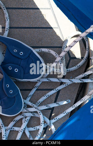 Nahaufnahme einer Verankerung Seil mit einer verknoteten Ende um eine Klampe auf einem hölzernen Pier nautische Festmacher Seil gebunden. Schließen Boot Seil gebunden auf Abbildung 8 Keil H Stockfoto