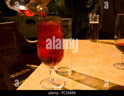 Aus einer Flasche in ein Glas gegossen auf eine Tabelle mit Schatten Trinken Stockfoto