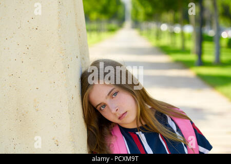 Blonde kind Schüler Mädchen sand gelangweilt Gesicht Geste im Park Stockfoto