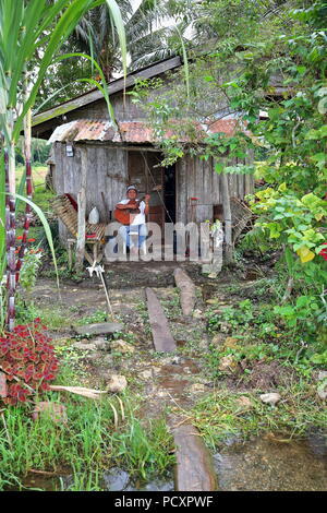 Carmen, Philippinen. Oktober 17, 2018: Philippinische Mann spielt Gitarre und singt, während der Rest sitzt auf der Veranda seines Hauses nach einem ganzen Tag arbeiten i Stockfoto