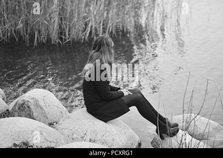 Die Frau in der Nähe des Wasser sitzen Stockfoto