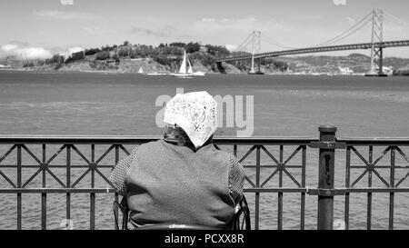 San Francisco, CA, USA - 21. Juli 2018: Schwarz und Weiß Rendering von unidentfied ältere Dame mit einem Schal auf dem Kopf mit Blick auf den Ozean mit der Stockfoto