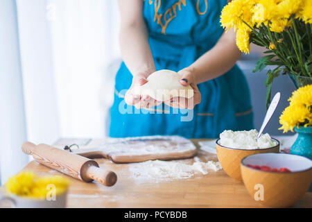 Die Frau arbeitet mit dem Test, auf dem Tisch liegt ein Nudelholz und Mehl. Stockfoto