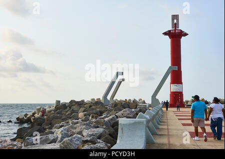 COATZACOALCOS, VER/MEXIKO - Aug 3, 2018: die Menschen zu Fuß und Angeln am Wellenbrecher auf der Flussmündung. Ein rotes Radio Beacon gezeigt Stockfoto