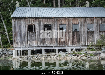 Eine vernachlässigte alten Holzschuppen mit Beton, Metall und Glas dach fehlt von den Fenstern erstreckt sich von der Küste über die Gezeiten. Stockfoto