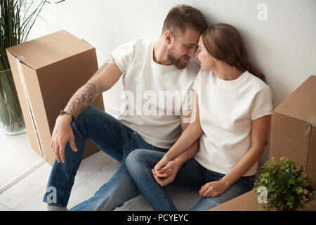 Junges Paar sitzen auf dem Boden der gekauften Wohnung halten sich an den Händen Stockfoto