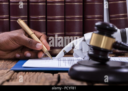 Roboterhand Unterstützung eine Person, die für die Unterzeichnung von Dokumenten im Gerichtssaal Stockfoto