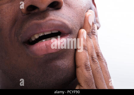 Nahaufnahme eines Mannes mit Zahnschmerzen vor weißem Hintergrund Stockfoto