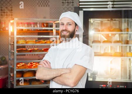 Portrait einer jungen schönen Bäcker mit frischem Brot und einem Ofen im Hintergrund. Stockfoto