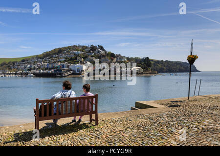 Urlauber sitzen auf einer Bank in der Bayard Cove, Dartmouth, über den Fluss Dart, kingswear an einem hellen Sommertag Stockfoto