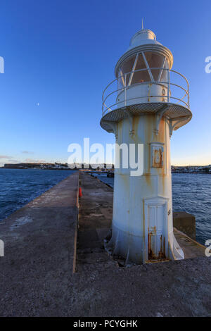 Einen kleinen weißen Leuchtturm am Ende der Mole im Hafen von Brixham, Brixham, Devon, hebt sich von einem klaren, blauen Himmel Stockfoto