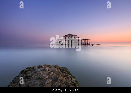 Die Ruinen der West Pier in Brighton bei Sonnenuntergang und einem niedrigen Spring Tide Stockfoto