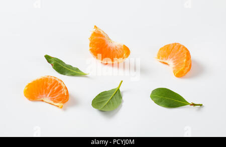 Segmente und Blätter von Reif tangerine auf weißem Hintergrund Stockfoto