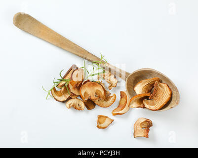Handvoll getrocknete Pilze und lange Löffel aus Holz auf weißem Hintergrund Stockfoto