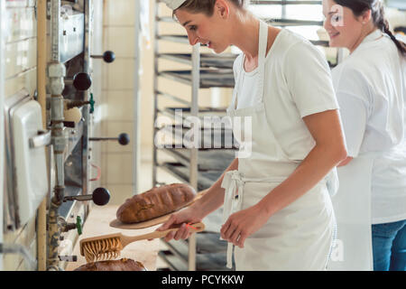 Team von zwei Bäcker Vorbereitung und Beschichtung Brot Stockfoto