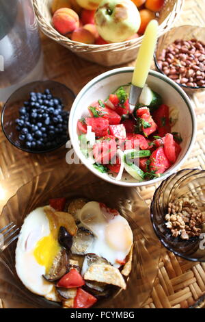 Ein Blick auf die Tabelle mit einer einfachen und Proteinen und Vitaminen reich gesund und reichlich Sommer Frühstück mit Gemüse, Beeren, Nüsse, Früchte und gebratene Eier Stockfoto