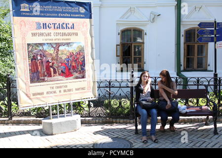 Ukrainische Damen nehmen Rest auf der Werkbank auf Sommertag auf dem Gebiet Kiew Pechersk Lavra (Kloster von Höhlen) in der Nähe der Ausstellung über Ukrainische mittelalterlichen Lebens Stockfoto