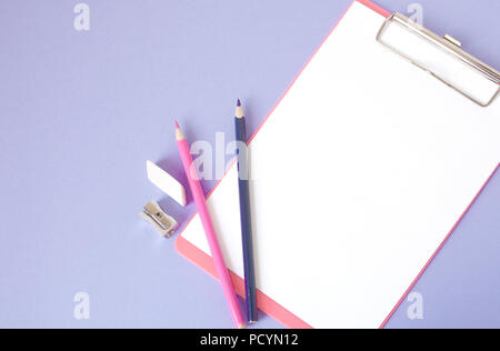 Bunte, fröhliche, bunte Bleistifte sind unten in einem Winkel und einem Notebook für Ihren Text auf einem violetten Hintergrund entfernt. Stockfoto