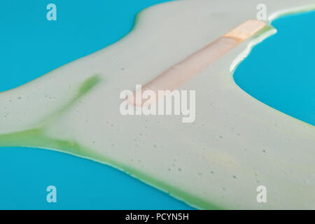 Seitenansicht gelb Popsicle vollständig schmelzen auf blauem Hintergrund Stockfoto