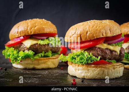 Hamburger mit Rindfleisch Burger und frischem Gemüse auf dunklem Hintergrund. Leckeres Essen. Stockfoto