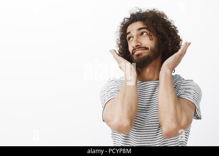 Innen- schuss von Sorglos gut aussehender bärtiger Kerl mit Afro Frisur, weg schauen und lächeln, mit verträumten Ausdruck, die Palmen und das Festhalten der Ne Stockfoto