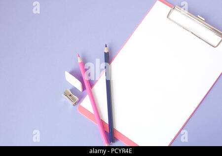 Bunte, fröhliche, bunte Bleistifte sind unten in einem Winkel und einem Notebook für Ihren Text auf einem violetten Hintergrund entfernt. Stockfoto